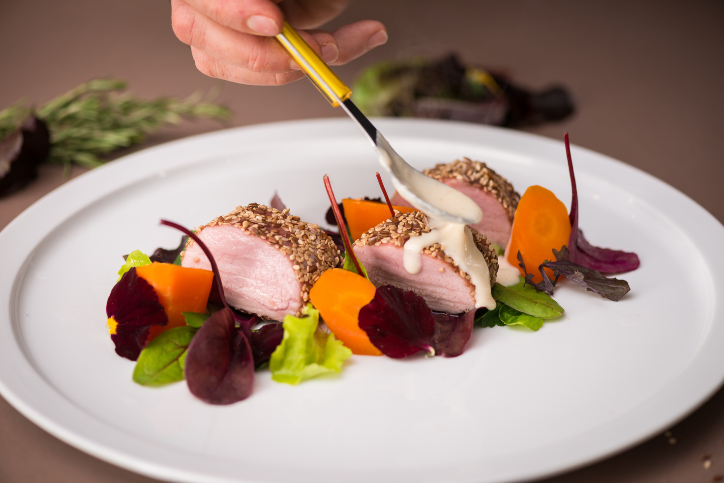 Professional chef preparing meal in private house: Garnishing pork roast dish